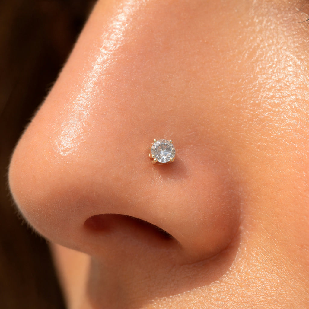 A photorealistic close-up of a diamond nose pin on a nose, displayed in natural daylight to show sparkle and metal warmth. Alt: Diamond nose pin close-up under natural light