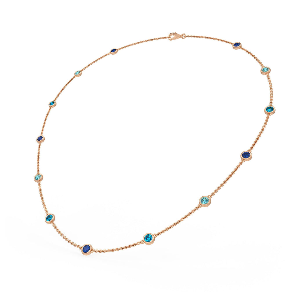 A gold chain necklace with small round bezel-set blue and turquoise stones, displayed on a clean white background