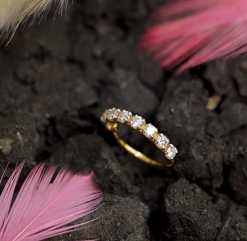 Gold nose stud with diamonds on black textured surface 