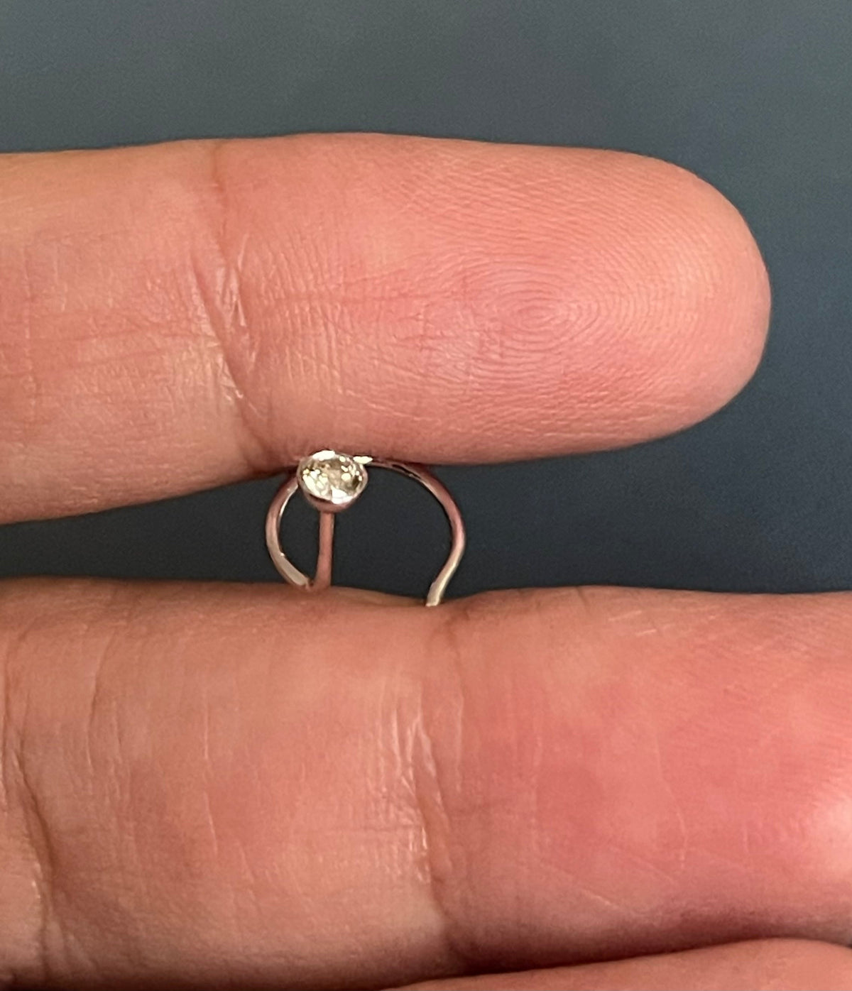 Gold ring with a diamond on a finger against a dark background