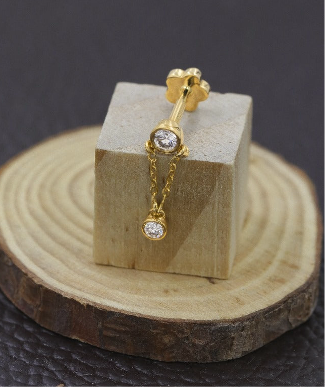 A single earring featuring a diamond stud with a gold chain drop