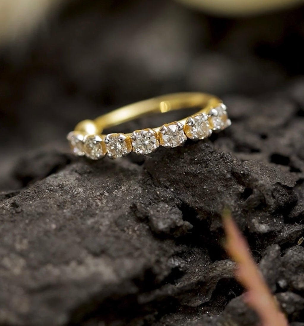 Gold nose stud with diamonds on a dark, textured surface