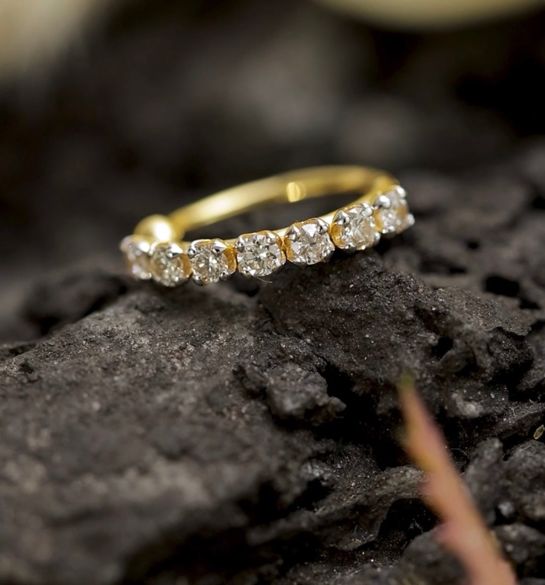 Gold nose stud with diamonds on a dark, textured surface