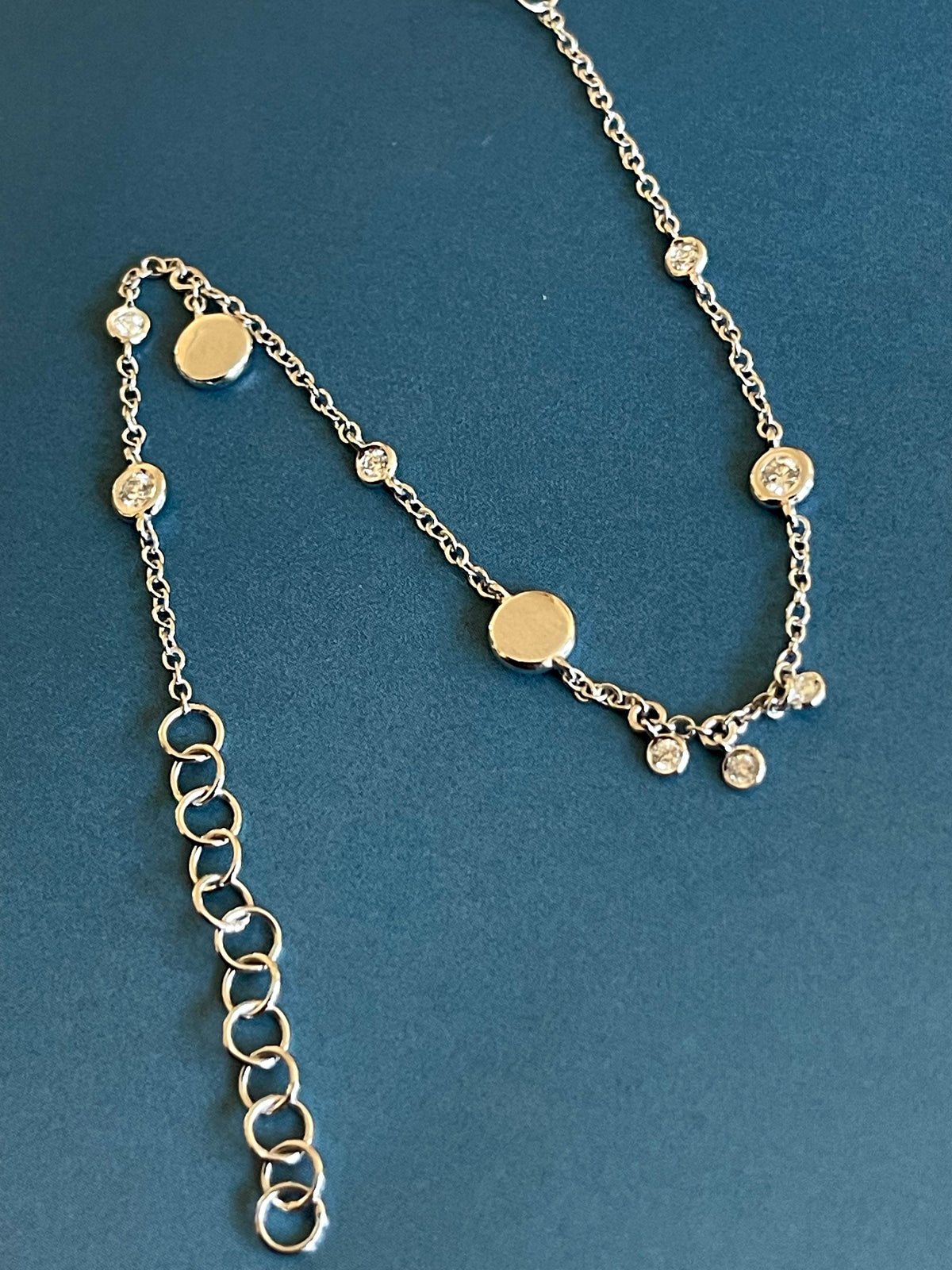 Bracelet en or blanc 18 carats serti de diamants (0,15 carat) avec breloques en forme de disque et pendentifs clos.
