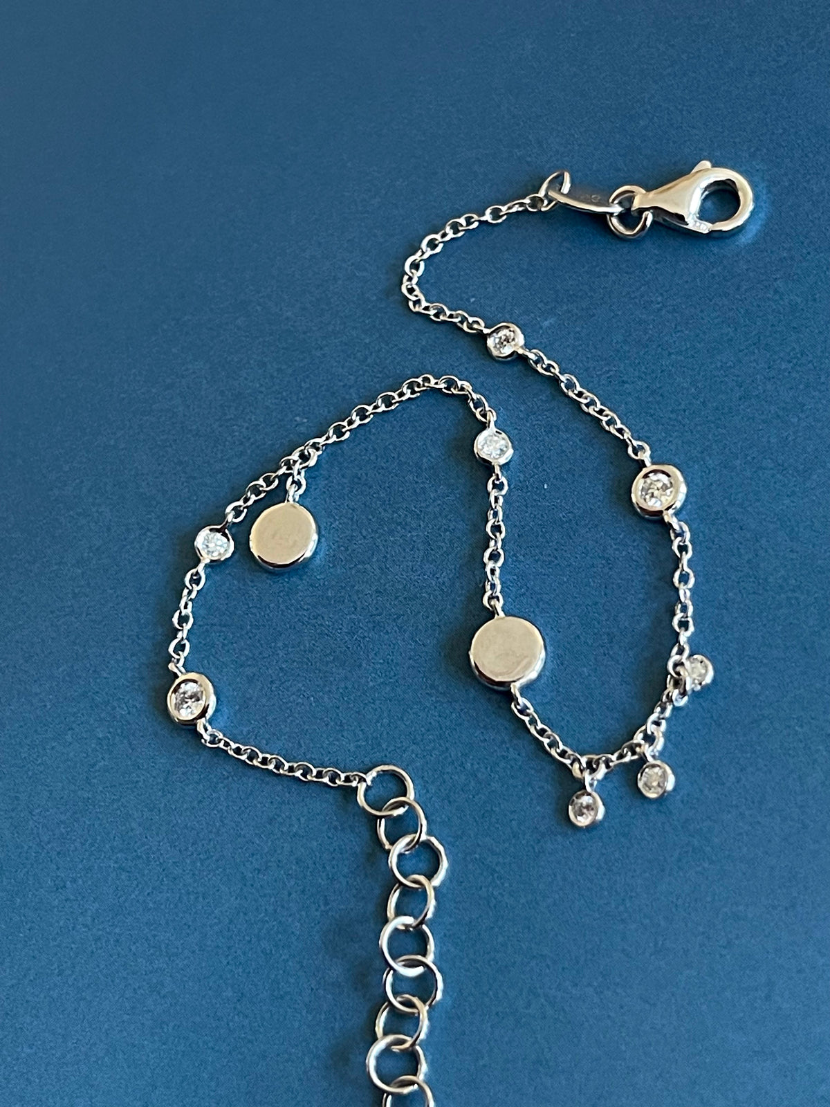 Bracelet en or blanc 18 carats serti de diamants (0,15 carat) avec breloques en forme de disque et pendentifs clos.