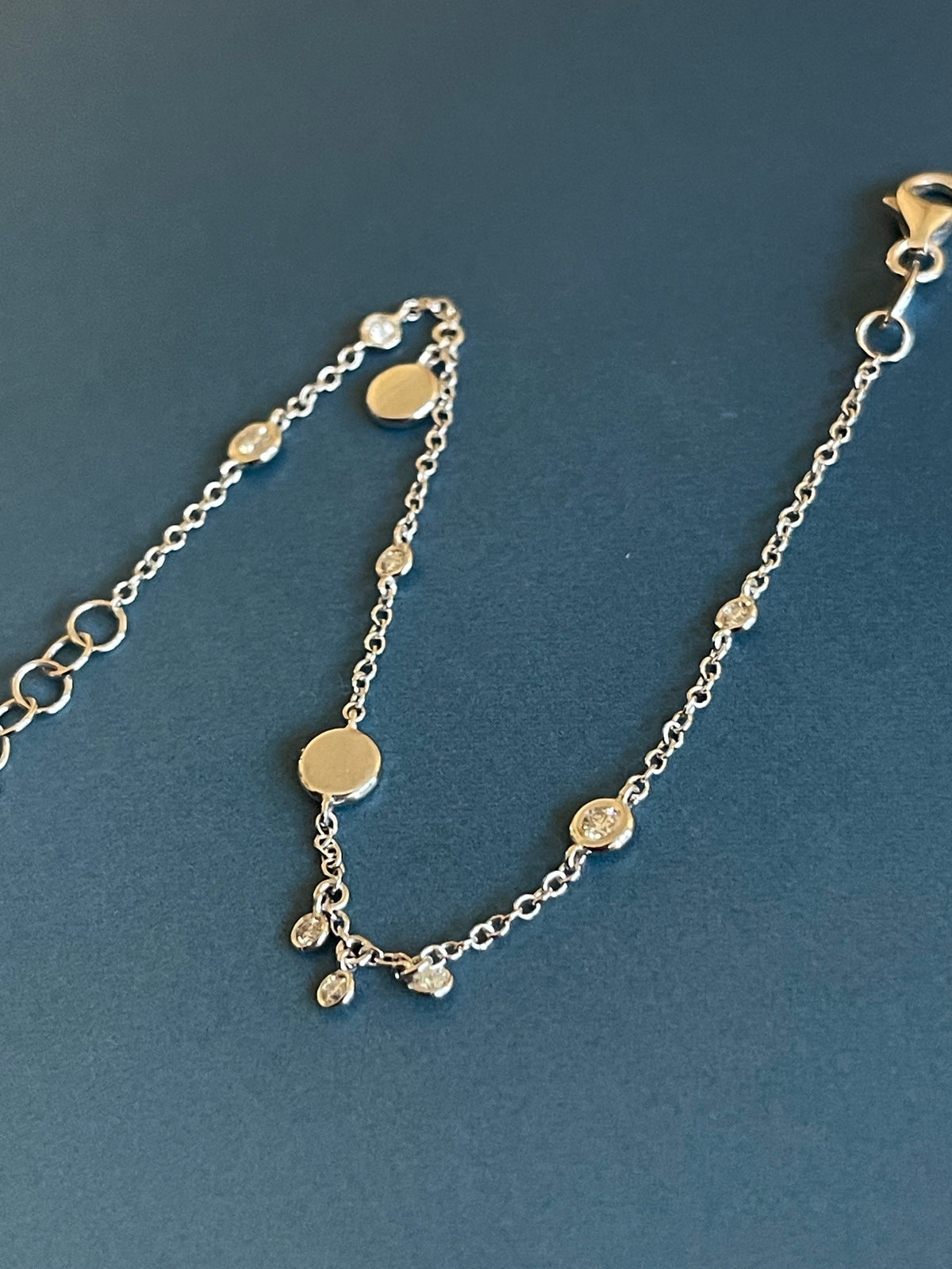 Bracelet en or blanc 18 carats serti de diamants (0,15 carat) avec breloques en forme de disque et pendentifs clos.