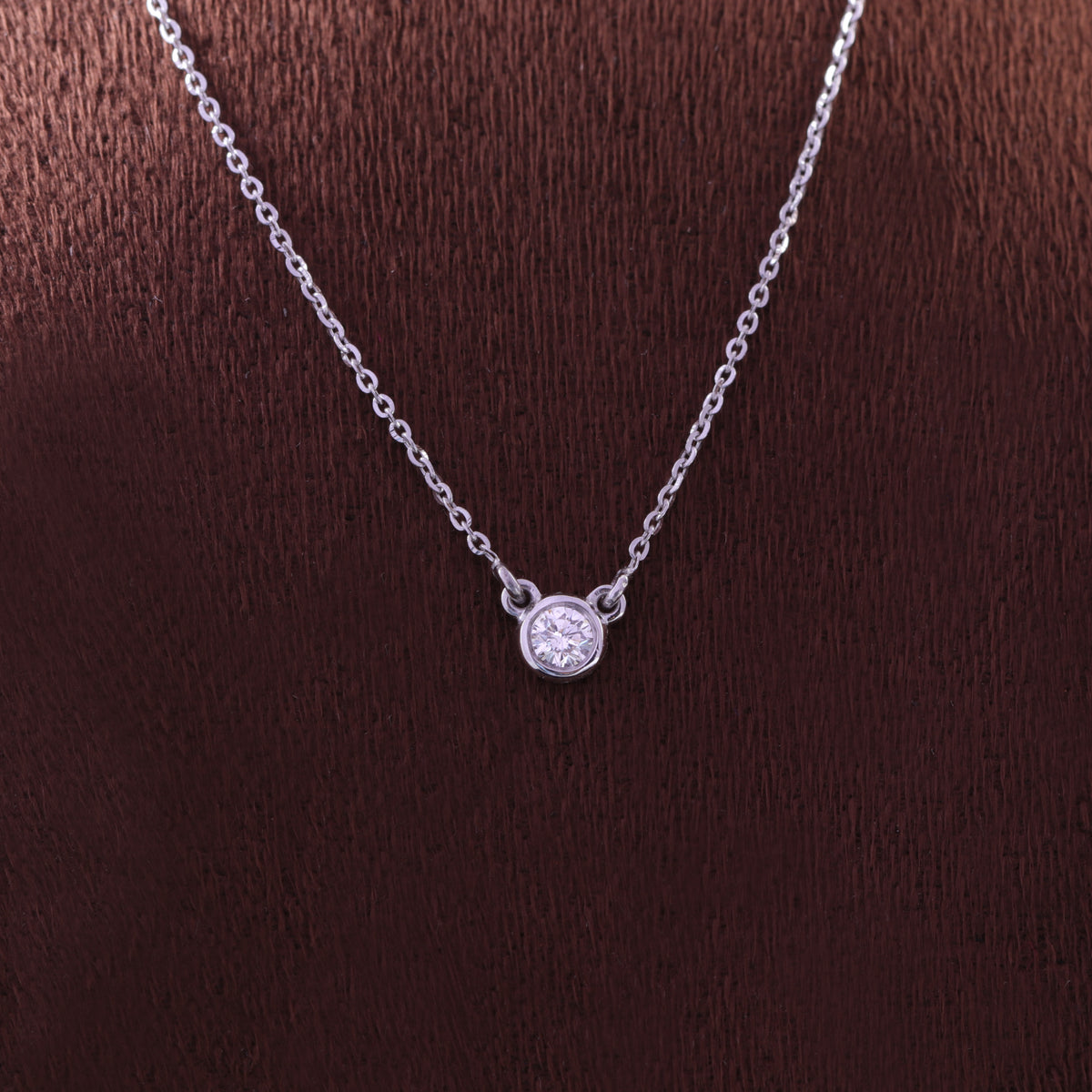 Round solitaire diamond secured in a rose gold bezel setting