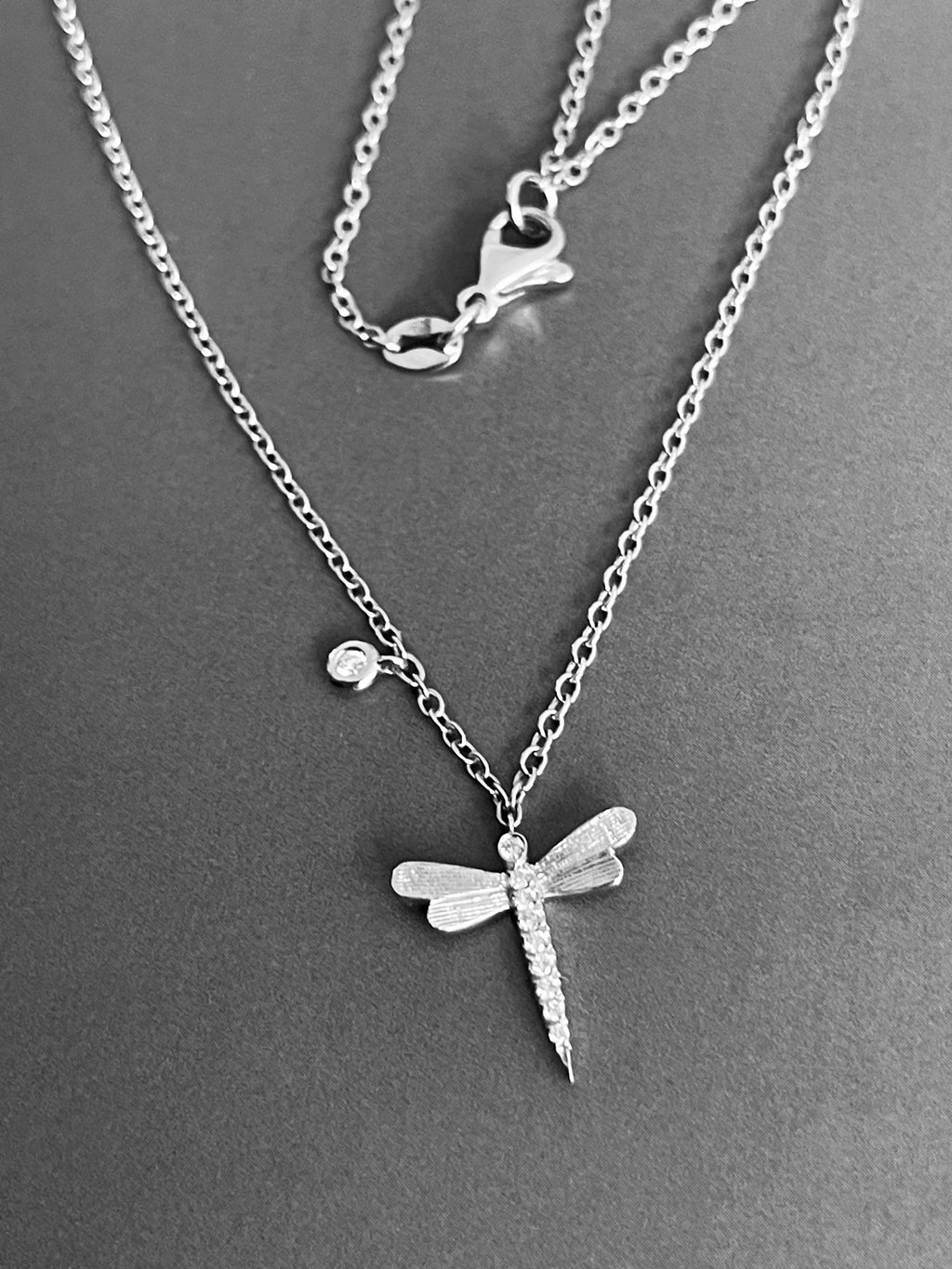Collier en or blanc 18 carats avec pendentif libellule et breloque solitaire, orné de diamants.
