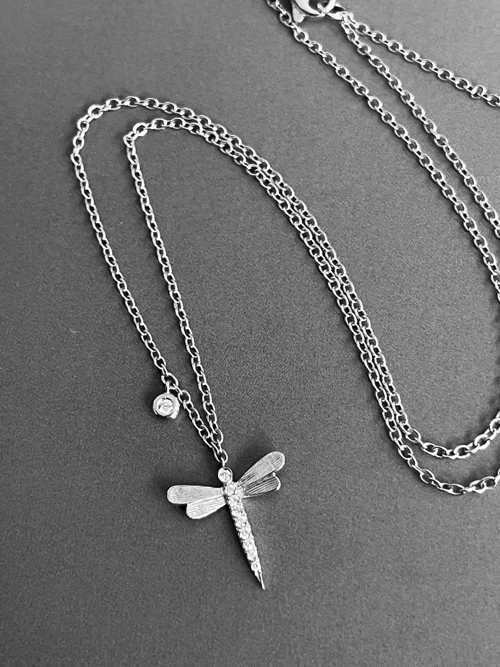 Collier en or blanc 18 carats avec pendentif libellule et breloque solitaire, orné de diamants.