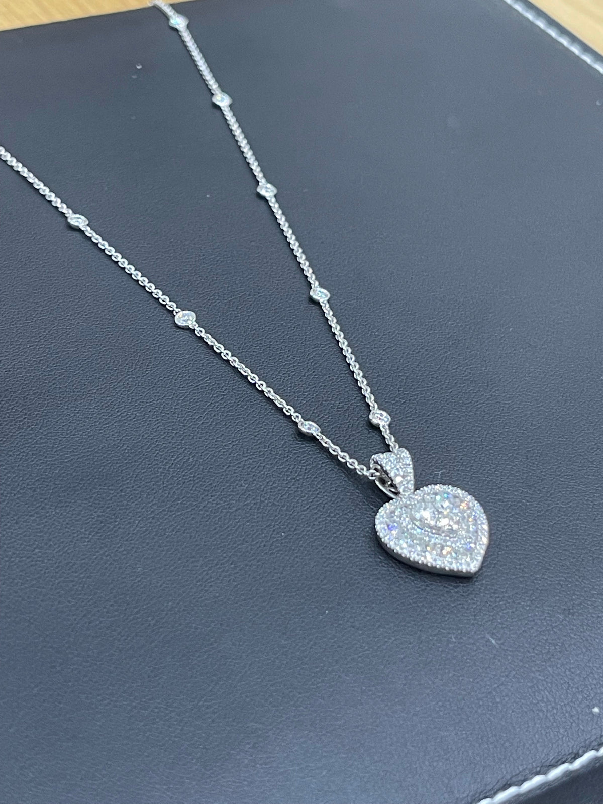 Collier en or blanc serti de diamants en forme de cœur et orné d'une chaînette de diamants dispersés